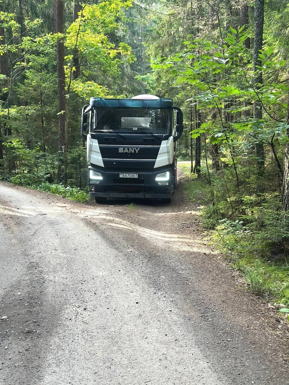 Автобетоносмеситель на узкой лесной грунтовой дороге по пути к участку